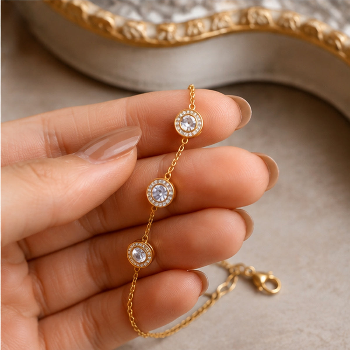 Close-up lifestyle detail of dainty gold-tone crystal bracelet held in hand