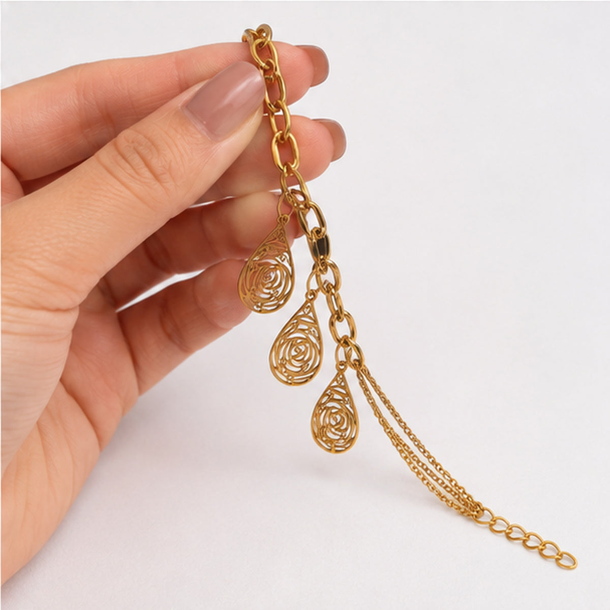 Gold teardrop filigree charm bracelet held in hand