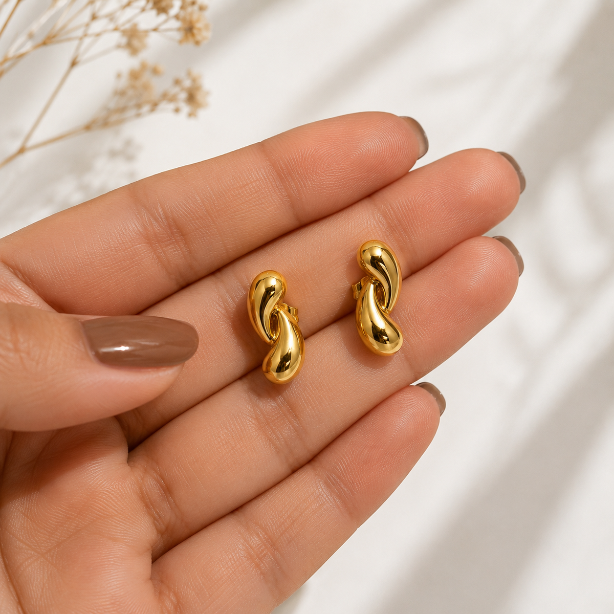 PRISA Gold Twisted Knot Stud Earrings held in hand