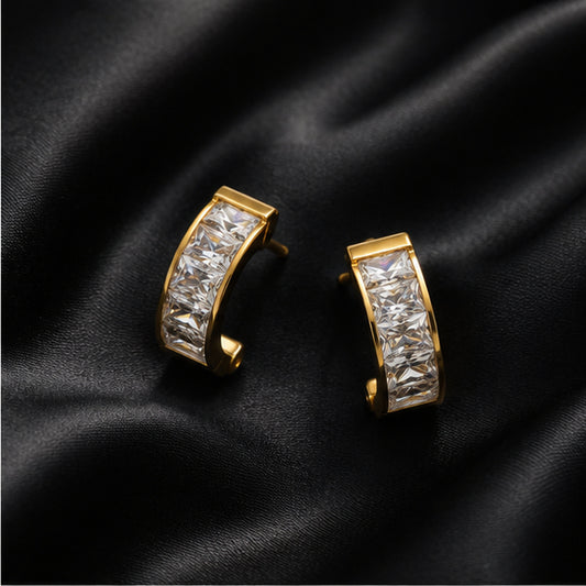 Gold-tone crystal huggie earrings on black satin