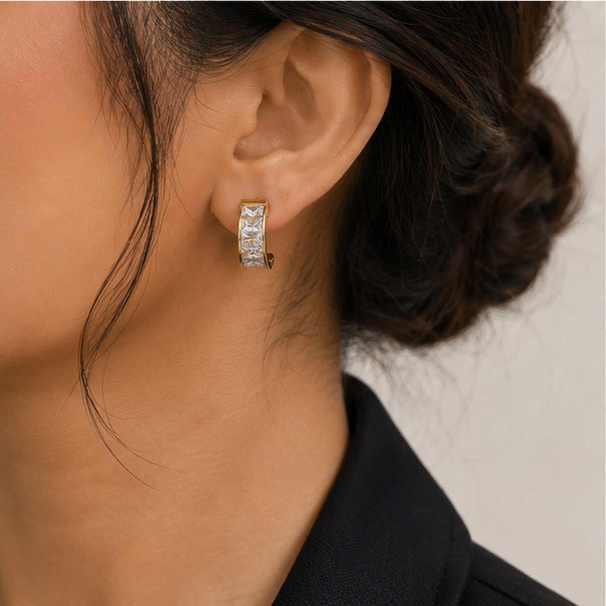 Woman wearing gold-tone crystal huggie earrings