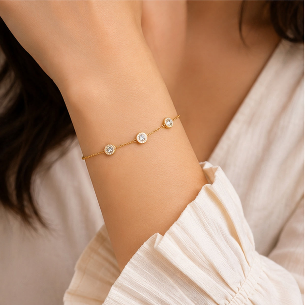 Dainty gold-tone crystal bracelet worn on a woman's wrist with a light outfit