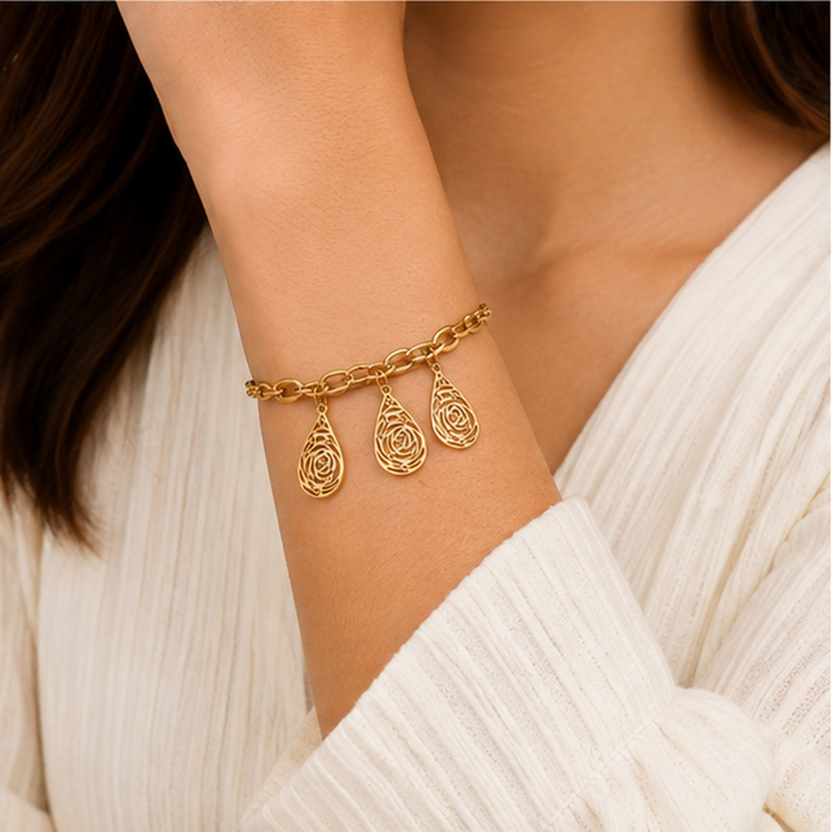 Gold teardrop filigree charm bracelet worn on wrist