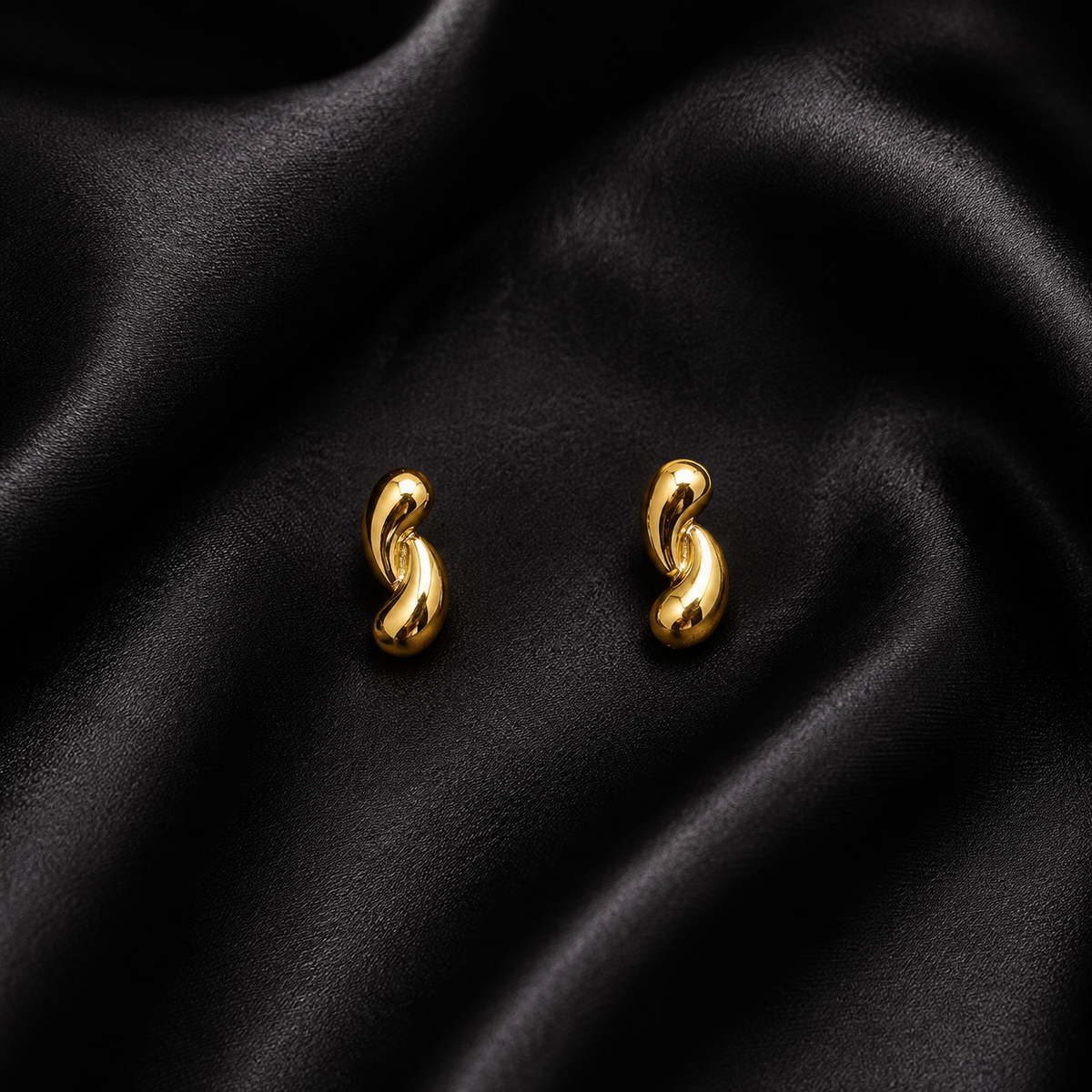 PRISA Gold Twisted Knot Stud Earrings on black satin